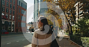 Happy attractive female enjoys the atmosphere of autumnal New York and turns to camera, smiling