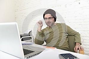 Happy attractive hipster businessman working with computer laptop at home office