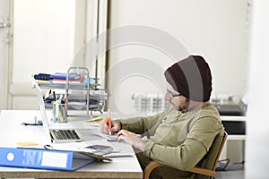 Happy attractive hipster businessman working with computer laptop at home office