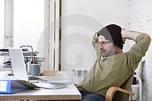 Happy attractive hipster businessman working with computer laptop at home office