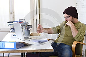 Happy attractive hipster businessman working with computer laptop at home office