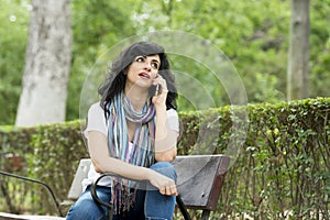 Happy attractive latin woman talking and texing on her smart phone.