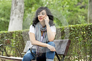 Happy attractive latin woman talking and texing on her smart phone.