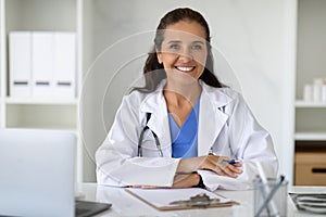 Happy attractive mature lady doctor posing at workplace at clinic