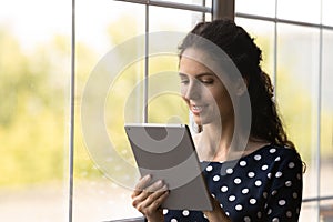 Happy attractive millennial latin woman using digital computer tablet.