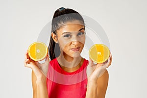 Happy attractive sporty woman holding glass of fresh orange juice and orange fruit