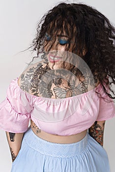 Happy attractive woman with beautiful tattoos in pastel clothes