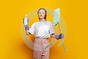 Happy attractive woman with household tools in hands posing against brigth orange studio wall banner background. Cleaning concept