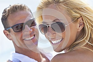 Un felice e attraente l'uomo e la donna paio di occhiali da sole e sorridente sole in spiaggia.