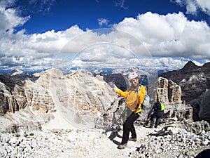 Happy attractive woman mountain climber gives a thumbs up on a mountain peak in the Dolomites
