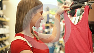 Happy attractive woman in red t-shirt shopping in mall buying clothes. Consumerism shopaholism concept