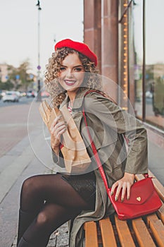 Happy attractive woman smiling and turning back at us in the street. Woman in red beret and red handbag outdoor