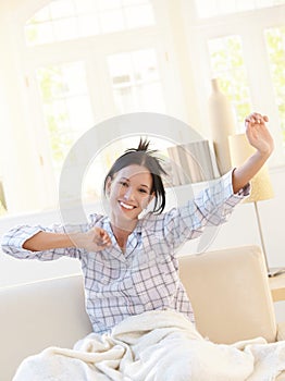 Happy attractive woman stretching in pyjama