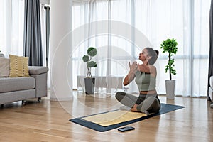 Happy attractive young business woman in active sport wear sitting on stretching muscles at her apartment after or before the work