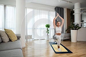 Happy attractive young business woman in active sport wear sitting on stretching muscles at her apartment after or before the work