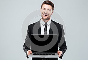 Happy attractive young businessman holding blank screen laptop