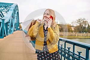 Happy attractive young caucasian blonde hair 30s woman in casual dress smiling in camera, holding eco kraft shopping