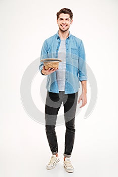 Happy attractive young man holding hat and asking for money