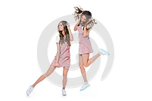 happy attractive young twins dancing and listening to music