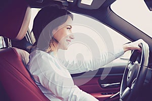 Happy attractive young woman driving a modern car