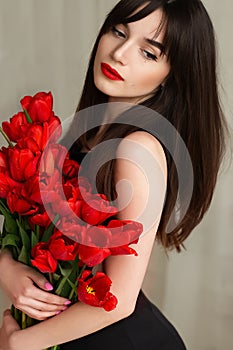 Happy attractive young woman with flowers. Beauty brunette girl with tulips bouquet. Beautiful sensual woman holding