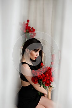 Happy attractive young woman with flowers. Beauty brunette girl with tulips bouquet. Beautiful sensual woman holding