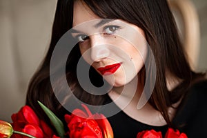 Happy attractive young woman with flowers. Beauty brunette girl with tulips bouquet. Beautiful sensual woman holding