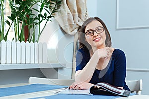 Happy attractive young woman reading magazine in cafe