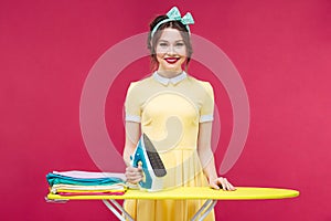 Happy attractive young woman standing and ironing clothes