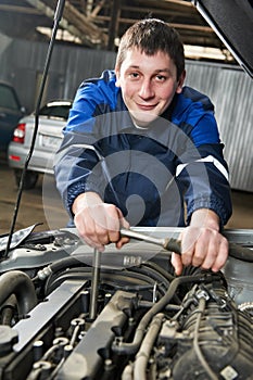 Happy automotive mechanic at work with wrench