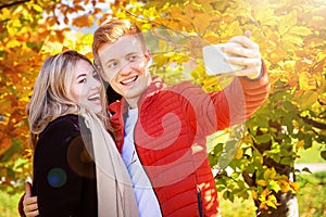 Happy autumn couple taking selfie (photo) in fall park.