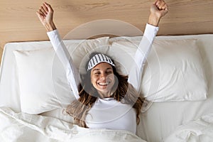 Happy awakened woman took off mask stretching after night sleeping