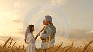 Happy baby in the arms of the farmer`s father and mother. little daughter, dad and mom play in wheat field. baby travels