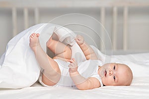 Happy baby on the bed in the morning. Textiles and bed linen for children. A newborn baby has woken up or is going to bed