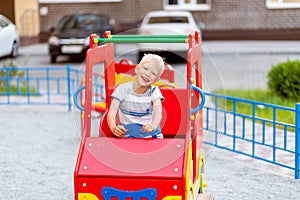 Happy baby boy 5-6 years old playing on the Playground in the yard in the summer. Children`s lifestyle