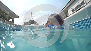 Happy baby boy dives under the water in the swimming pool. An underwater shot