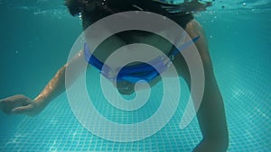 Happy baby boy diving under the water in the swimming pool. An underwater shot