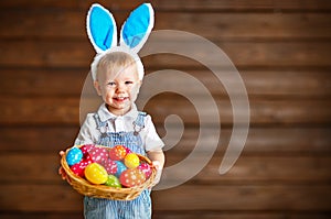 Happy baby boy in Easter bunny suit with basket of eggs