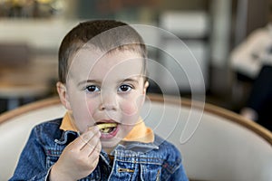 A happy baby boy eats French fries. fast food. European. boy 2 years old close-up eating french fries