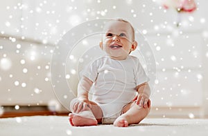 Happy baby boy or girl sitting on floor at home