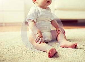 Happy baby boy or girl sitting on floor at home