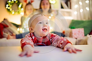 Happy baby boy having fun with his family in a cozy living room on Christmas eve. Celebrating Xmas at home. Winter evening with