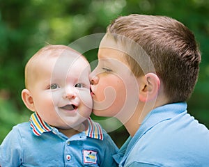 Happy baby boy kissed by his brother photo