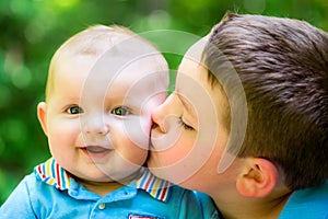 Happy baby boy kissed by his brother photo