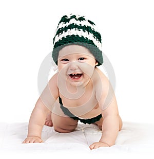 Happy baby boy in knitted hat crawling over white