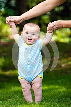 Happy baby boy learning to walk on grass