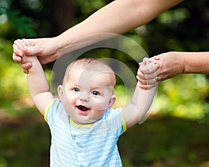 Happy baby boy learning to walk on grass