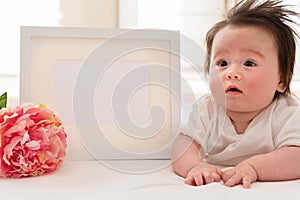 Happy baby boy with photo frame and flower