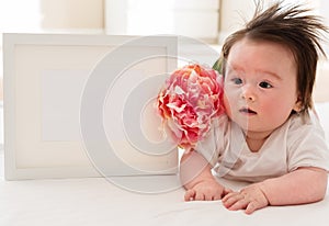 Happy baby boy with photo frame and flower