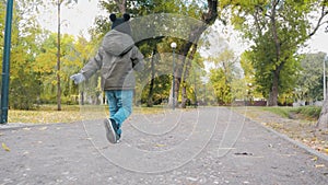 Happy baby boy running in autumnal park. Little child playing on autumn walk. Autumnal forest with golden leaves